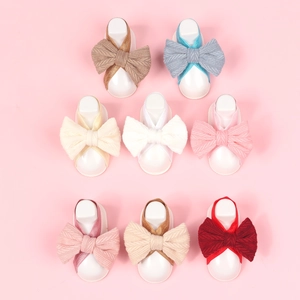 Detail view of 8-piece newborn set featuring knitted wheat ear bow headbands and foot straps