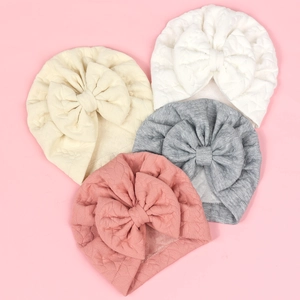 Close-up of diamond-textured knit baby turban hats with large bows in multiple soft colors