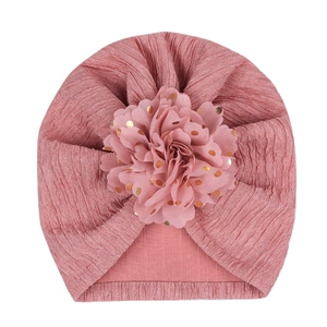 Detailed texture of pink ruffled baby turban hat with golden dot floral embellishment