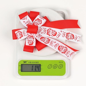 Detail of Christmas bow hair clip on a digital scale showing 11.4g weight clearly