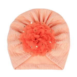 Detail view of baby turban hat with large 3D flower and golden polka dots pattern