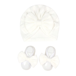 Detail of white waffle knit newborn turban hat and bow booties set in soft cotton fabric
