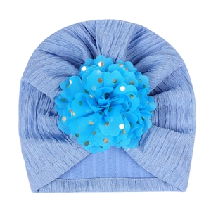 Detail of baby sky blue knit turban hat with large gold-dotted floral fabric embellishment