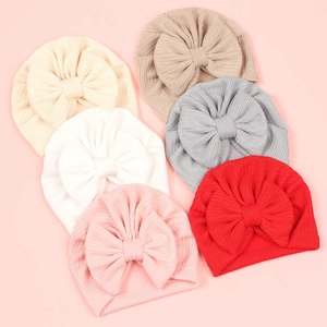 Détail de six bonnets turbans colorés pour bébé avec de grands nœuds et texture côtelée