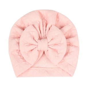 Pink infant turban hat with large bow and jacquard texture on white background
