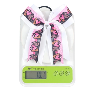 Pink and white bow hair tie with LOVE print and heart patterns on a digital scale