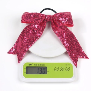 Close-up showing the weight of a pink sequined bow hair tie on a digital scale