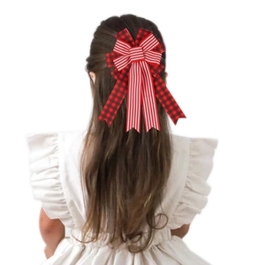 Detail of red plaid and striped Christmas hair bow on a young girl's head with long ribbons