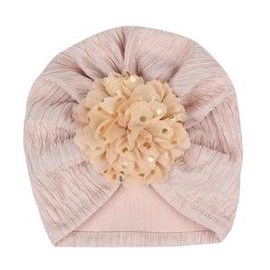Detailed texture of pink baby turban hat featuring a large gold foil polka dot mesh flower