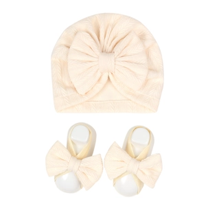 Detail of ribbed knit baby hat and matching socks with large bow accents in cream white