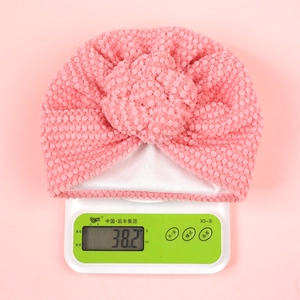 Bonnet bébé en polaire rose sur balance montrant le poids léger de 38,2g en détail