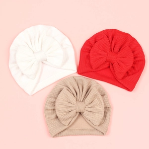 Détail de bonnets pour bébé à nœud en blanc, rouge et kaki avec texture tricotée