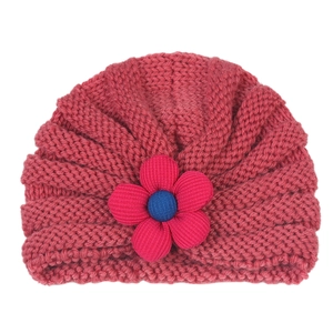 Detail of baby knitted turban hat featuring pink floral petal and blue center contrast