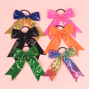 Close-up of six colorful sequin bow hair ties neatly arranged on a pink background