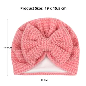 Pink infant beanie with waffle texture and large bow, dimensions 19x15.5cm for baby warmth