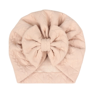 Detail view of baby bow beanie featuring pink quilted texture and oversized bow ornament