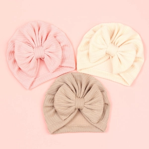Vue détaillée de bonnets pour bébé en maille gaufre avec de grands nœuds décoratifs