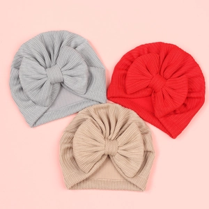 Détail de la texture en maille gaufre des bonnets à nœud en gris, rouge et kaki