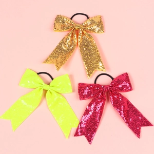 Close-up of three sparkling sequined bow hair ties in gold, green, and pink colors