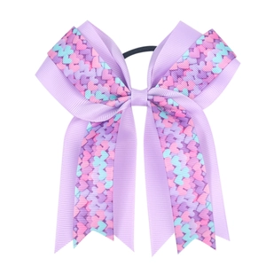 Detail of purple ribbon bow hair tie with colorful heart patterns and elastic band
