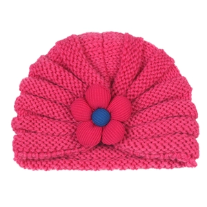 Detailed close-up of rose red knitted baby beanie with a blue 3D five-petal flower design