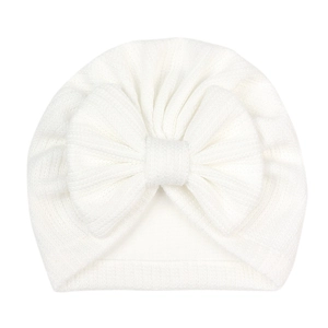 Détail du bonnet tricoté blanc perle pour bébé avec gros nœud et texture côtelée