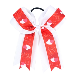 Detail of red and white bow hair tie with heart patterns and black elastic band