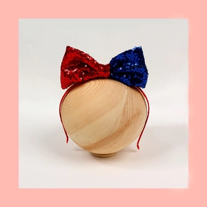 Dettaglio della fascia per capelli con fiocco di paillettes rosso e blu per feste