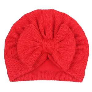 Gros plan d'un bonnet turban tricoté rouge pour bébé avec un grand nœud décoratif