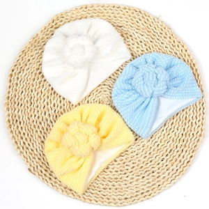 Détail de bonnets pour bébé en maille douce avec nœuds beignets en blanc, bleu et jaune