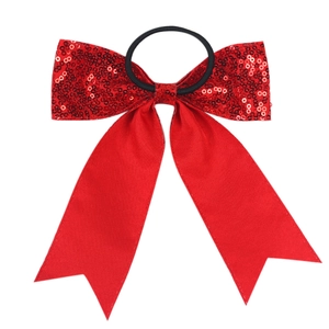 Detail of red sequin bow hair tie with long satin tails on a clean white background