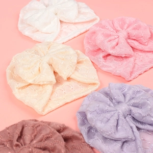 Détail de bonnets à nœud pour bébé en cinq couleurs pastel avec dentelle crochetée