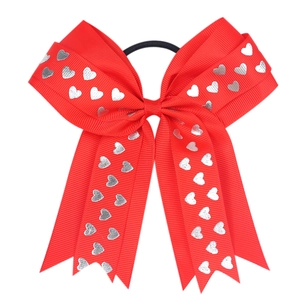 Close-up of red grosgrain hair bow with silver heart prints and elastic band for girls