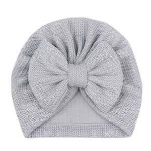 Gros plan détaillé du bonnet pour bébé en tricot gris clair avec grand nœud et texture