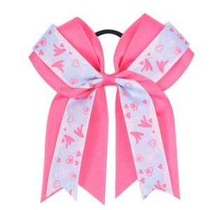 Detail of pink and blue oversized bow hair tie with heart and wing ribbon patterns