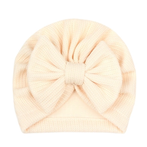 Détail de la texture en maille côtelée douce et du grand nœud sur ce turban pour bébé beige