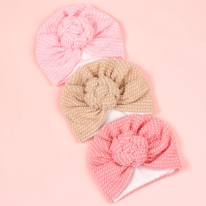 Détail de bonnets pour bébés en tissu gaufré avec nœuds décoratifs aux tons pastels doux