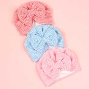 Soft double-layered baby beanies with large bows in pink and blue waffle texture
