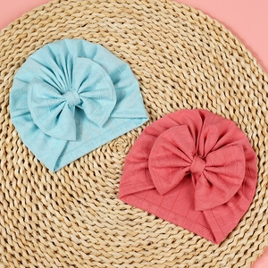 Detail of baby hats featuring diamond texture knit fabric and large bow accents