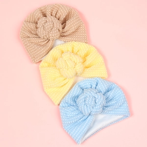 Détail du tissu à bulles et des grandes fleurs artisanales sur les turbans pour bébés