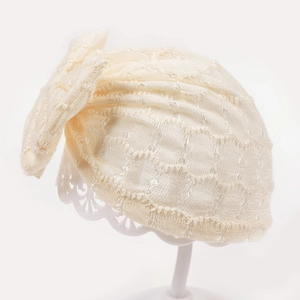 Texture détaillée du bonnet en dentelle pour bébé avec paillettes et motif évidé