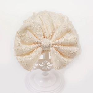 Texture détaillée du bandeau tricoté pour bébé avec grand nœud en tissu dentelle crème