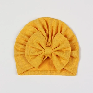 Close-up of vibrant yellow baby turban hat with large bow and waffle knit texture