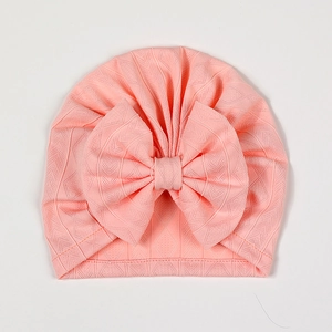 Detailed view of breathable diamond knit texture and oversized bow on coral baby hat