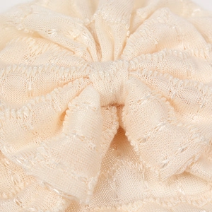 Détail macro de la dentelle tricotée respirante et du grand nœud sur bonnet bébé