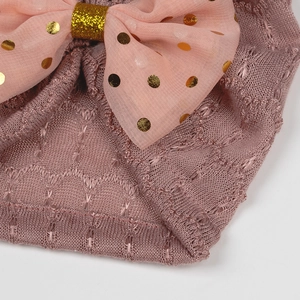 Détail d'un turban bébé rose avec un grand nœud à paillettes et une maille très douce