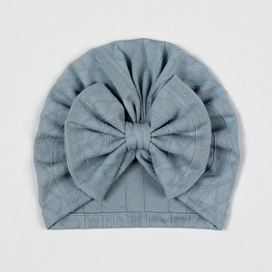 Detail view of light blue baby turban featuring a large bow and diamond mesh knit texture