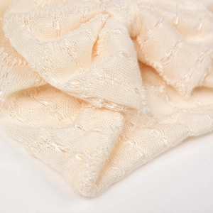 Détail macro du tricot crème avec motifs ajourés et fils de soie métalliques scintillants