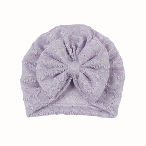Vue détaillée du bonnet turban pour bébé lilas avec un grand nœud et une texture tricotée