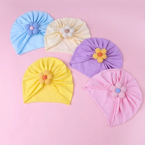 Detail view of five assorted color baby turbans with 3D flower petals in soft cotton